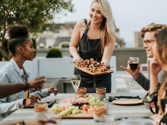 A woman serving food to a group of people at an outdoor table.
