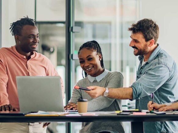 A group of people sitting around a table looking at a laptop, discussing new homes in GTA.