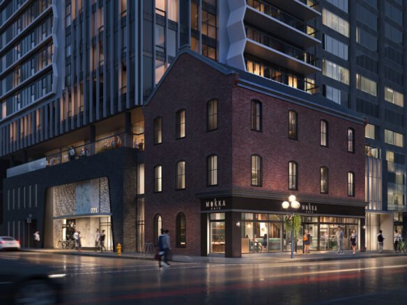 A nighttime city street scene showcases a modern building with a historic brick facade on the corner. The structure, under the glow of illuminated signage, attracts people walking along the wet sidewalk. Nearby modern skyscrapers surround the area, reminiscent of new condos in Brampton.