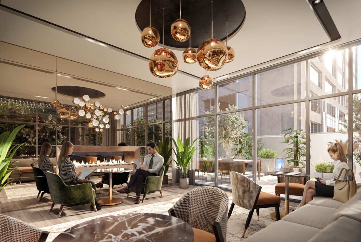 A modern lounge area in new homes showcases people seated around a fireplace, surrounded by green plants. The room features large windows, brown and beige seating, and contemporary copper pendant lights hanging from the ceiling, creating an inviting atmosphere.
