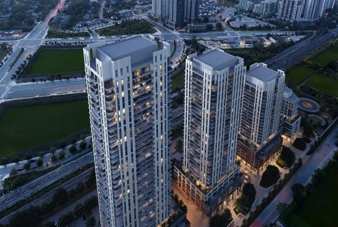 Aerial view of a modern residential high-rise complex during twilight, showcasing illuminated buildings and adjacent green spaces, with new condos in the background.