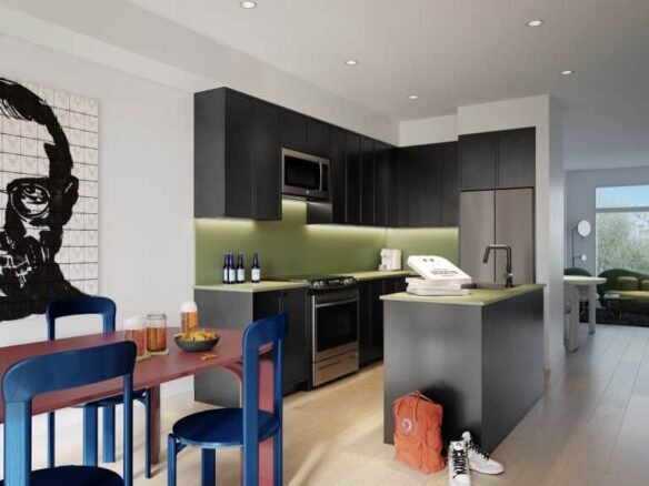 Modern kitchen with dark cabinetry and a green backsplash at Brooklin Towns. An island with a sink is in the center, accompanied by a stylish table with blue and red chairs. A red backpack is on the floor, and a pop art painting hangs on the wall. The text "C-1952 Kitchen" is in the top right corner.