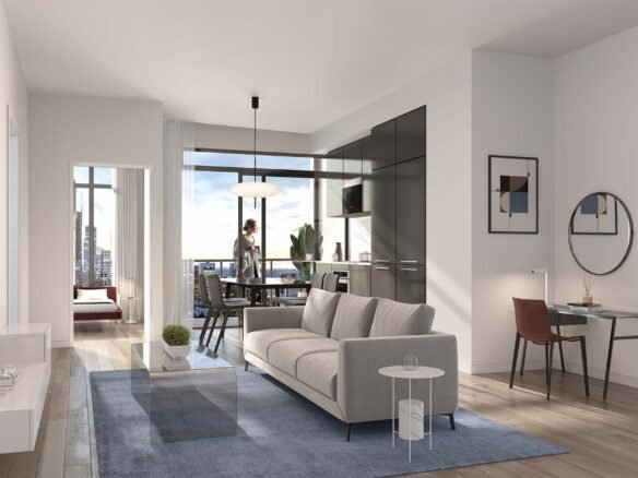 Modern apartment interior featuring an open living space with a grey sofa, blue rug, and mounted TV. The kitchen area has dark cabinets and a dining table with two chairs. A large window offers a view of the city skyline, reminiscent of new condos in GTA. A bedroom is visible in the background.