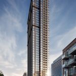 A towering modern skyscraper with sleek glass and steel architecture stands prominently under a partly cloudy sky. The building displays an elegant, grid-like facade with various reflections. Nearby, smaller buildings line the street, which has light traffic and several signs advertising new homes in GTA.