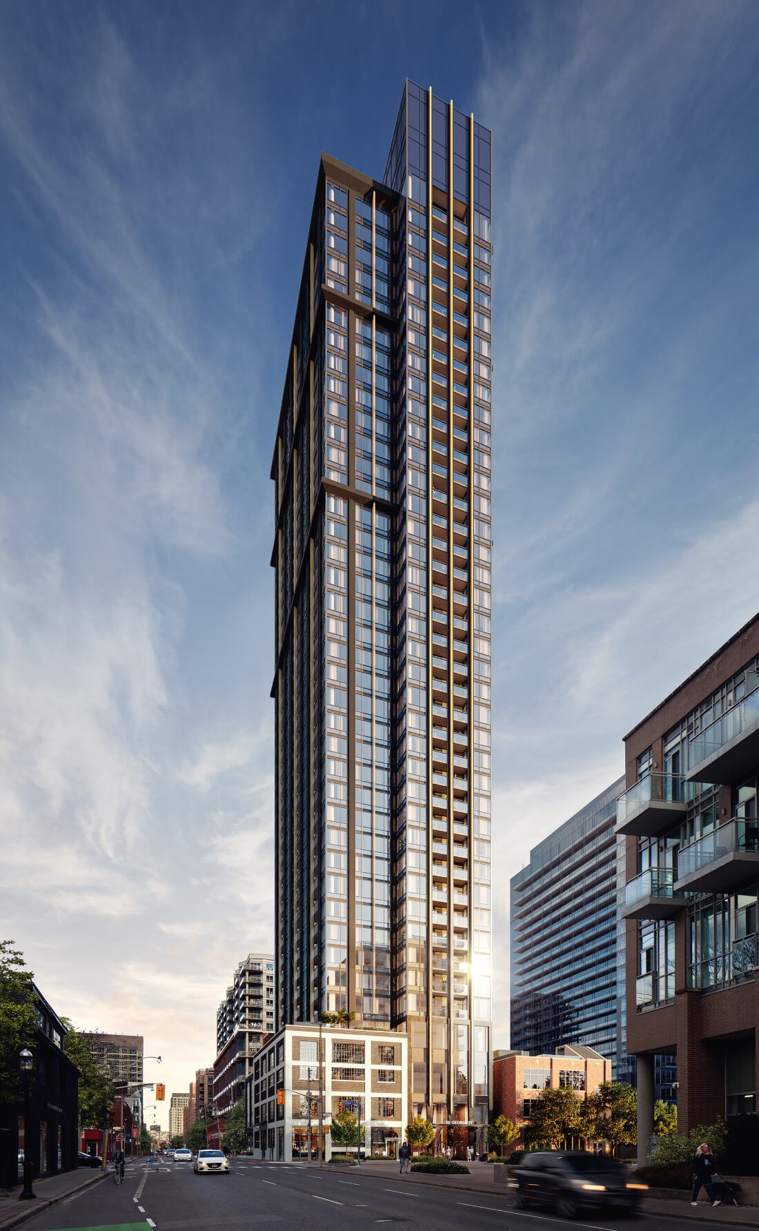 A towering modern skyscraper with sleek glass and steel architecture stands prominently under a partly cloudy sky. The building displays an elegant, grid-like facade with various reflections. Nearby, smaller buildings line the street, which has light traffic and several signs advertising new homes in GTA.