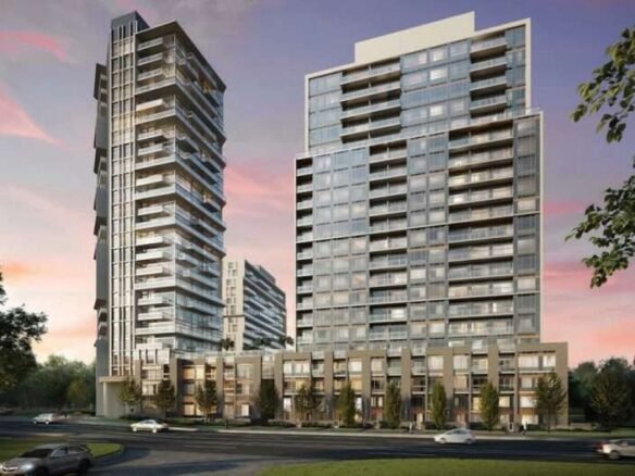 A modern residential complex featuring two adjacent high-rise buildings with numerous windows and balconies. In the foreground, a few cars are driving on a road curving in front of the buildings. Trees surround the area, with a vibrant sunset sky in the background, highlighting new condos in GTA.