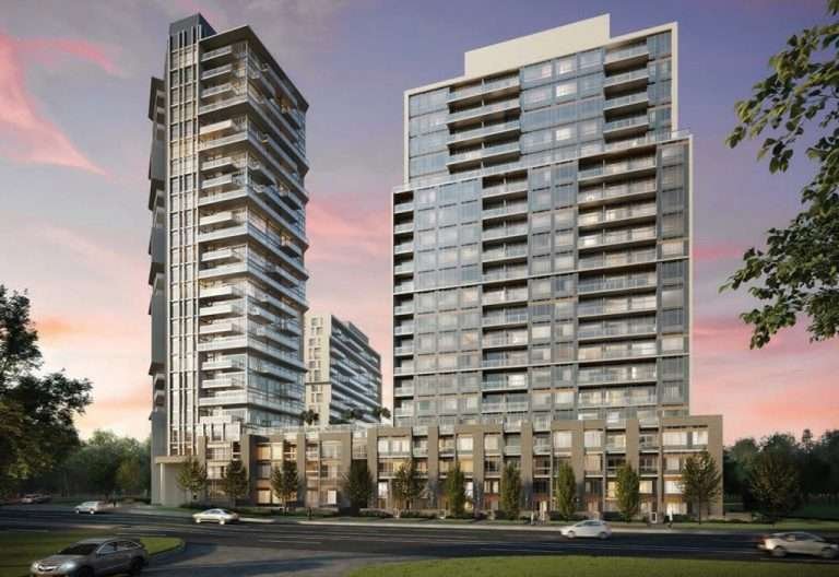 A modern residential complex featuring two adjacent high-rise buildings with numerous windows and balconies. In the foreground, a few cars are driving on a road curving in front of the buildings. Trees surround the area, with a vibrant sunset sky in the background, highlighting new condos in GTA.