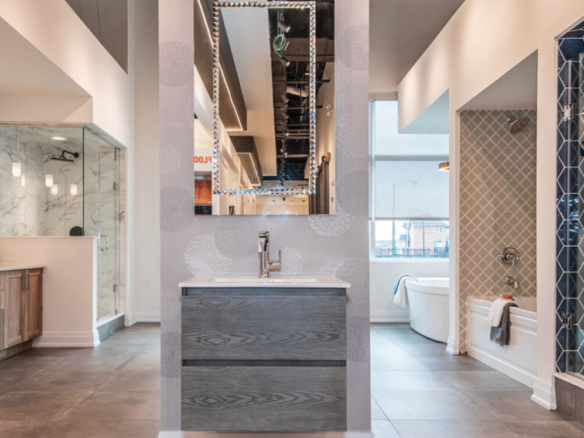A stylish showroom display featuring modern bathroom designs, perfect for pre-construction homes. The centered vanity with a rectangular mirror is flanked by diverse shower and bathtub setups showcasing contemporary tiles, fixtures, and finishes. The overall look is sleek and sophisticated.