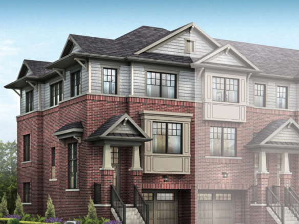 A three-story townhouse with a combination of red brick and gray siding. The building features multiple peaked roofs, large black-framed windows, and small front porches with black railings. Perfect for those seeking new homes in GTA, the landscaping includes green shrubs and trees.