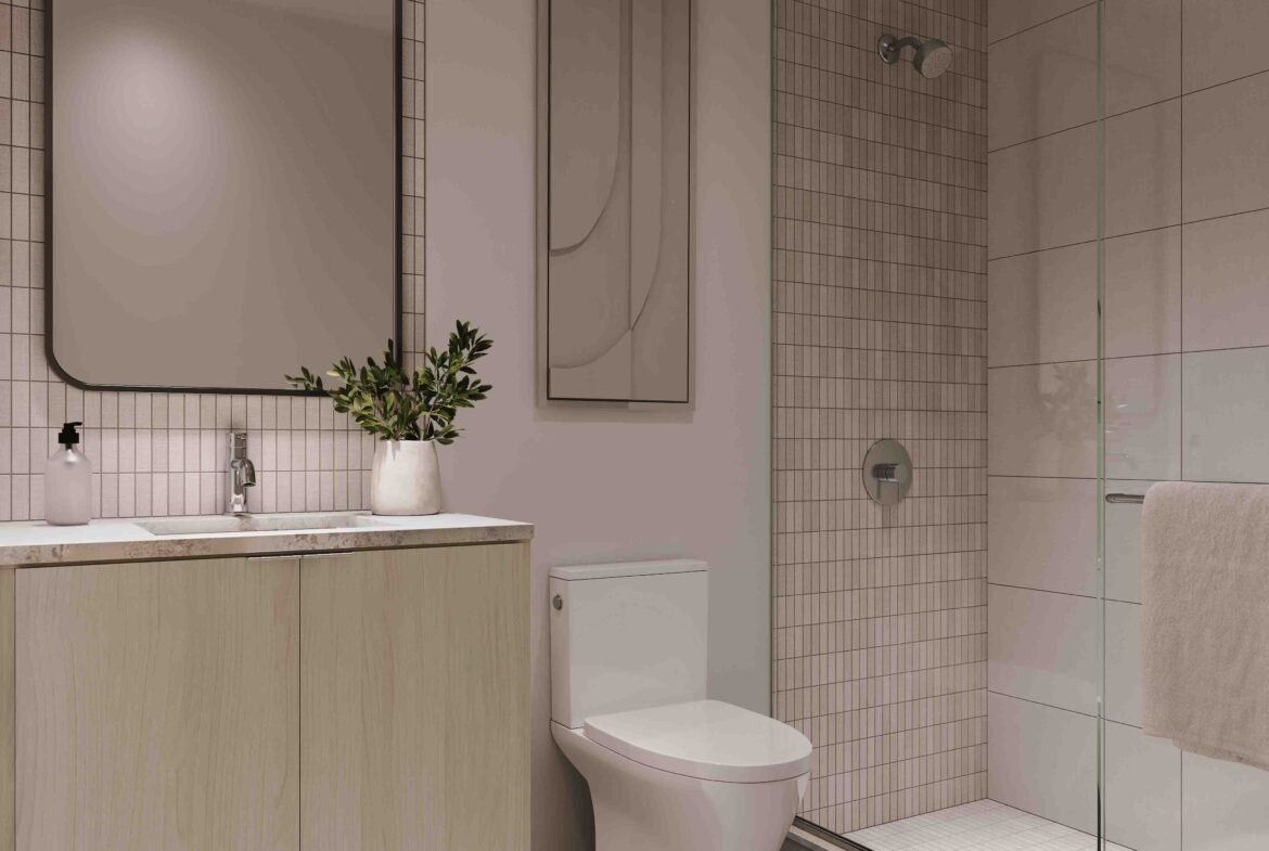 Modern bathroom in Sg Homes with soft pink walls, a wooden vanity with a rectangular mirror, a glass-enclosed shower, beige tiles, and subtle lighting.