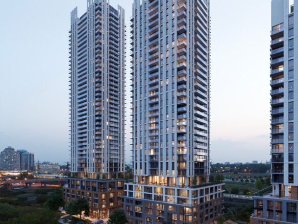 Aerial view of modern twin high-rise New condos at dusk, illuminated, with surrounding greenery and a road at the base.