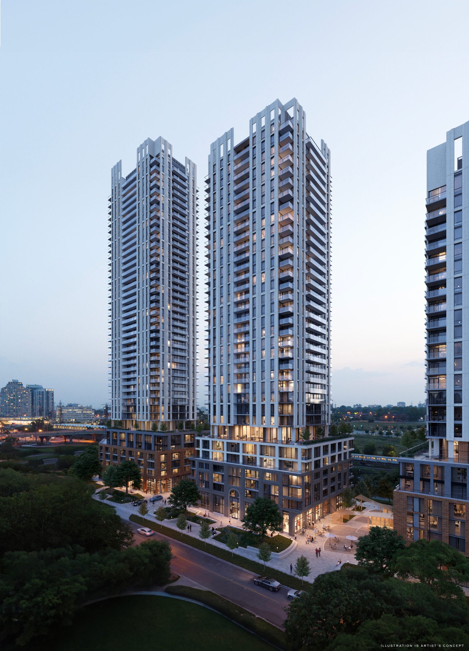 Aerial view of modern twin high-rise New condos at dusk, illuminated, with surrounding greenery and a road at the base.