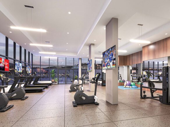 Interior of a modern gym featuring treadmills, exercise bikes, weight machines, and fitness balls. TVs mounted on walls and large windows in a well-lit space.