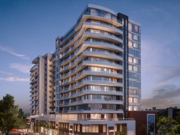 A modern, multi-story apartment building with numerous glass balconies is illuminated at dusk. The building has a sleek design with curved edges and ground-floor businesses. Surrounding it are well-lit streets, cars, trees, and pedestrians, showcasing the allure of new condos in GTA.
