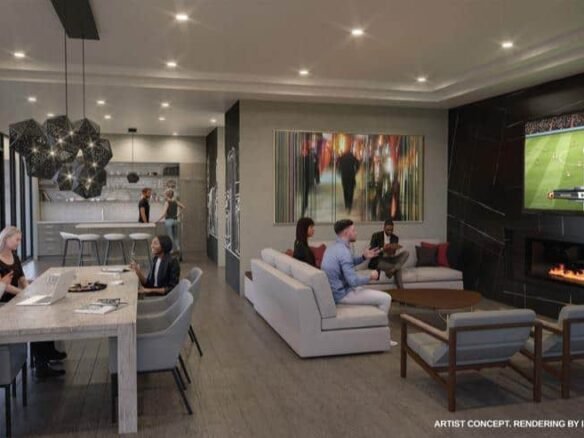 A modern living space in new homes showcases a group of people seated on sofas, watching a soccer game on a large wall-mounted TV. Nearby, others gather around a dining table with laptops and papers. The room, found in pre-construction homes, boasts floor-to-ceiling windows, contemporary lighting, and a fireplace.