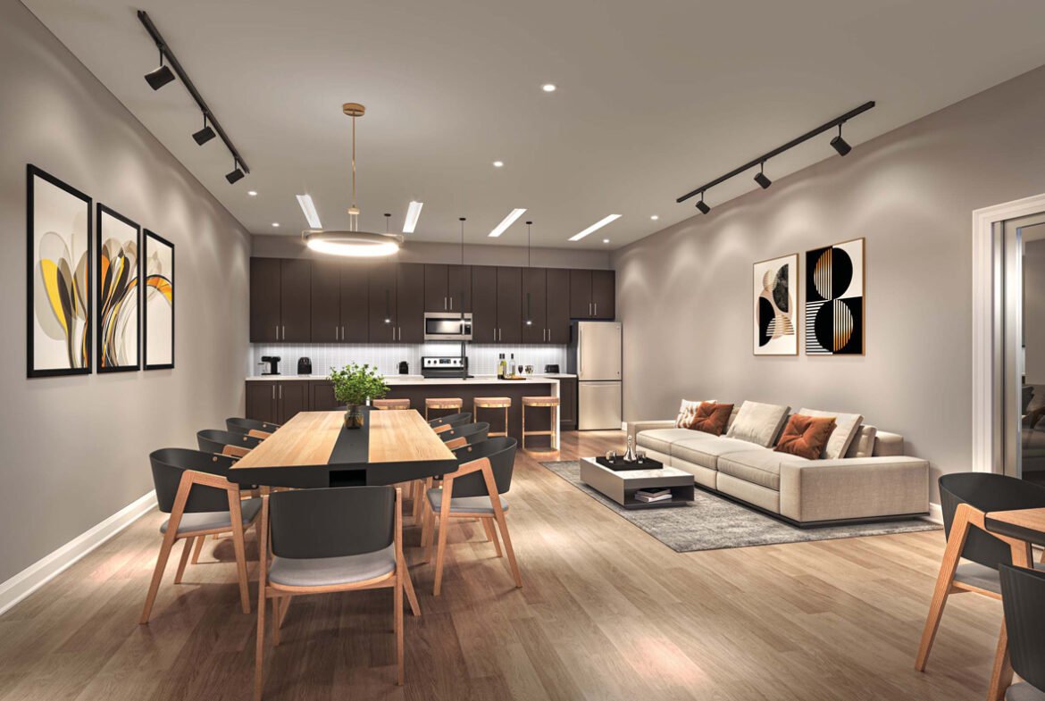Modern open-plan living space featuring a kitchen with dark cabinetry, a dining area with a large wooden table, and a lounge with beige sofa, all under warm ambient lighting in New Condos