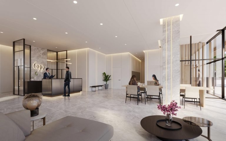 A modern, spacious lobby at Six99 Condos features marble floors and minimalist decor. Two individuals are conversing at a reception desk on the left, while on the right, two people work on laptops at a table. The space is brightly lit with natural and overhead lighting.