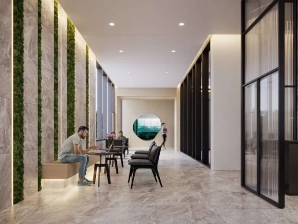 A modern indoor space in the Six99 condos features a marble floor and walls adorned with vertical green moss lines. Two people interact at a set of chairs and tables on the left, while another person walks in the background. Large glass panels and ambient lighting enhance the area.