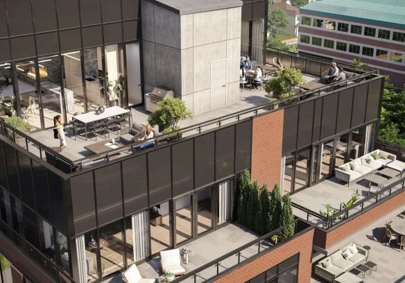 An aerial view of the modern Six99 Condos reveals a multi-story building with several spacious terraces. The terraces are furnished with outdoor seating, tables, and plants. A few people are seen enjoying the space, while trees and another building provide a picturesque background.