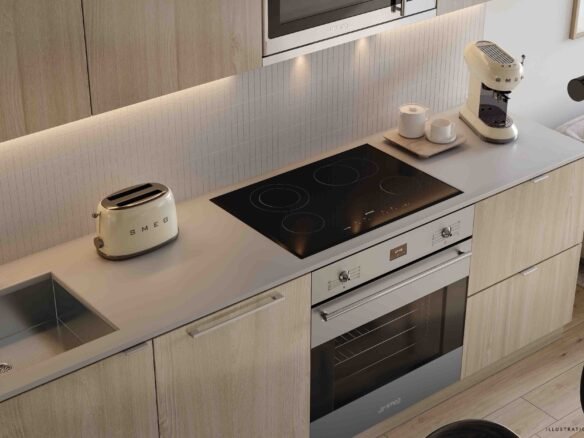 Modern kitchen interior featuring light wood cabinets, a sleek induction stove, built-in oven, and small appliances in a pre-construction home. A cozy seating area with a gray sofa is visible adjacent