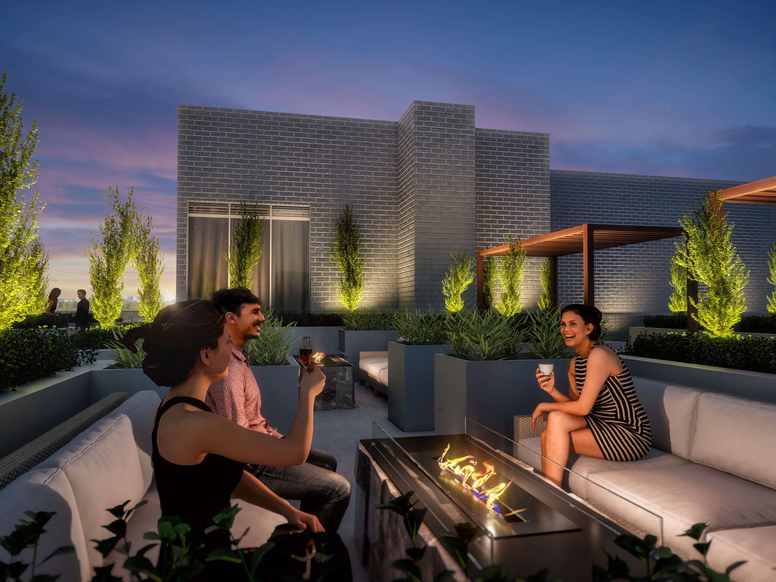 Three people are relaxing on a rooftop lounge in the evening, sipping drinks around a fire pit. The modern setting features brick buildings, lush greenery, and ambient lighting, perfectly complementing the dusky sky with its blend of purple and blue hues—a serene spot in a city known for its new homes.