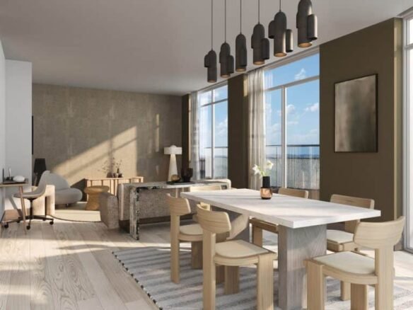 A modern, sunlit dining room in new homes in GTA featuring a light wood table surrounded by matching chairs, and pendant lights overhead, adjacent to a cozy living area with large windows.