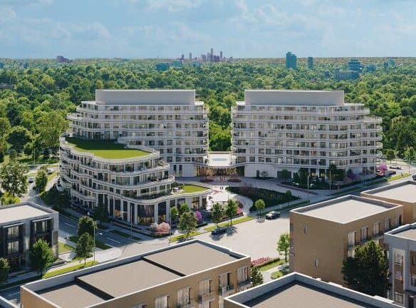 Aerial view of modern Sg Homes with lush green roofs, situated next to a dense tree park, with a distant city skyline under a clear blue sky.