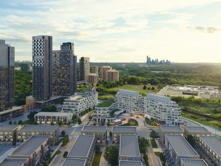 Aerial view of a modern urban development featuring various high-rise buildings and Pre construction Homes surrounded by green spaces, under a clear blue sky with distant cityscape.