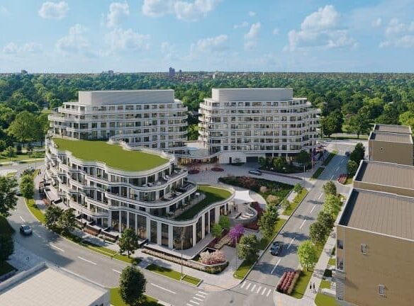 Aerial view of new condos in a modern residential complex showing two large buildings with curved designs, lush green terraces, and surrounded by paved streets.