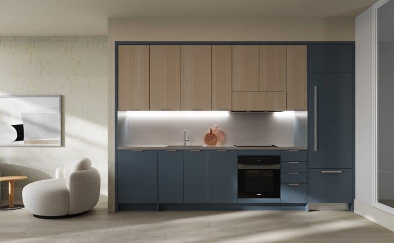 A modern kitchen with blue and wooden cabinets, stainless steel appliances, and a sink under bright task lighting in new condos.