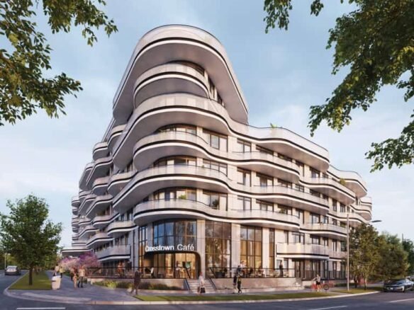 A modern, curvilinear building with multiple floors stands on a street corner. It features smooth, undulating balconies and large ground-floor windows. The Crosstown Café is visible on the ground floor, surrounded by trees and pedestrians.