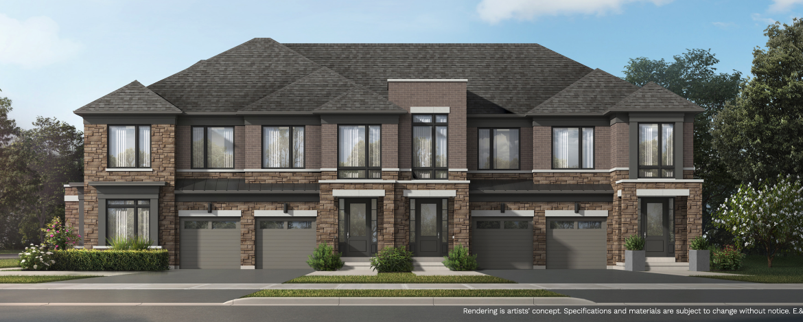 A modern townhouse complex with brick and stone exterior features two stories and attached garages. The building is surrounded by neatly trimmed bushes and trees under a clear blue sky, offering an appealing option for those seeking new condos in Brampton.