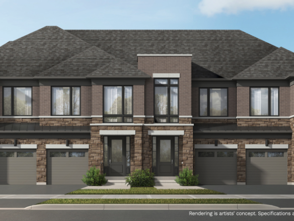 A modern townhouse complex with brick and stone exterior features two stories and attached garages. The building is surrounded by neatly trimmed bushes and trees under a clear blue sky, offering an appealing option for those seeking new condos in Brampton.