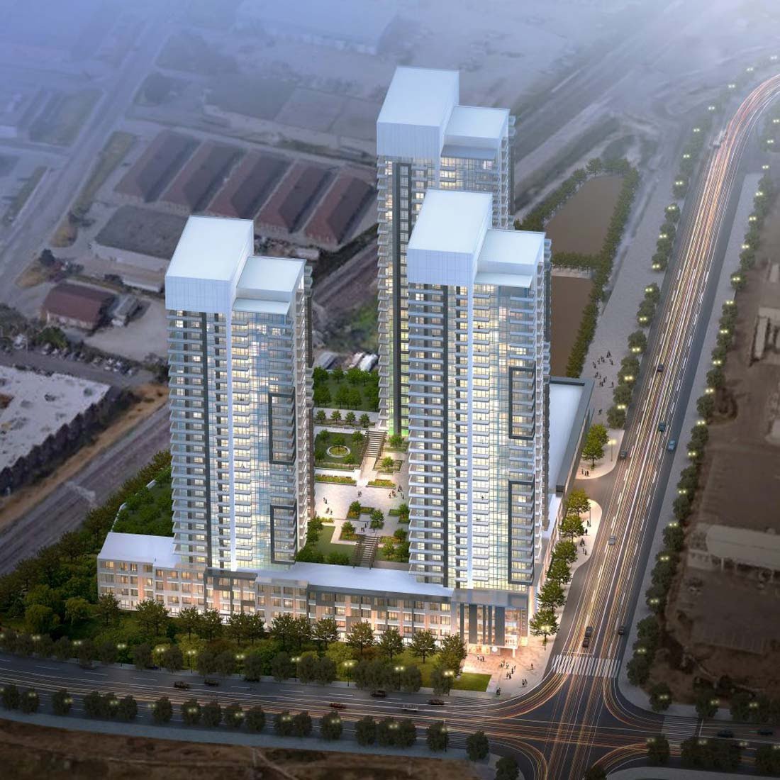 Aerial view of a modern, high-rise residential complex featuring three tall buildings with illuminated windows. The towers are connected by a green rooftop with landscaped gardens. These new condos in GTA are situated by a well-lit, bustling road lined with trees. Aerial view of a modern, high-rise residential complex featuring three tall buildings with illuminated windows. The towers are connected by a green rooftop with landscaped gardens. These new condos in GTA are situated by a well-lit, bustling road lined with trees.