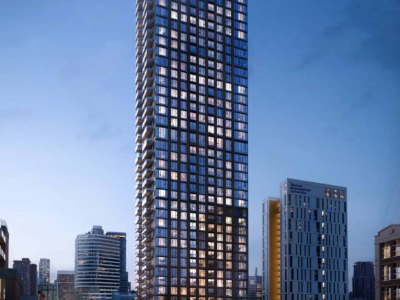 A towering skyscraper with illuminated windows stands against a twilight sky, surrounded by other buildings in a bustling urban area. Streetlights and car trails light up the busy road below, as nearby new condos in the GTA promise luxurious living above the vibrant city scene.