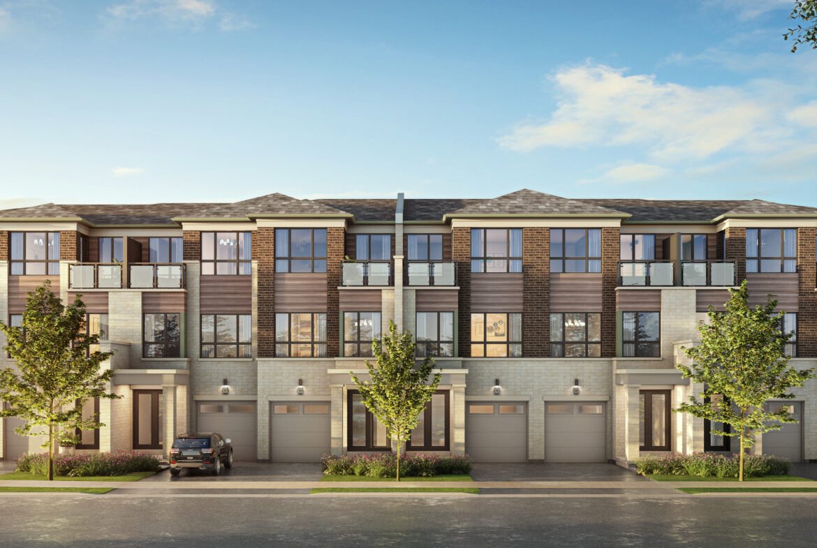 A modern three-story townhouse complex with a brick and siding exterior showcases large windows and balconies. Trees gracefully line the street, while a parked car rests in front. The sky is clear and blue, complementing these new homes in Brampton's serene setting.