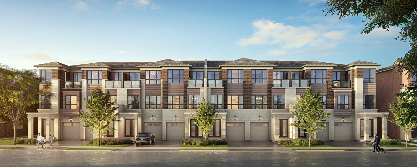 A modern three-story townhouse complex with a brick and siding exterior showcases large windows and balconies. Trees gracefully line the street, while a parked car rests in front. The sky is clear and blue, complementing these new homes in Brampton's serene setting.