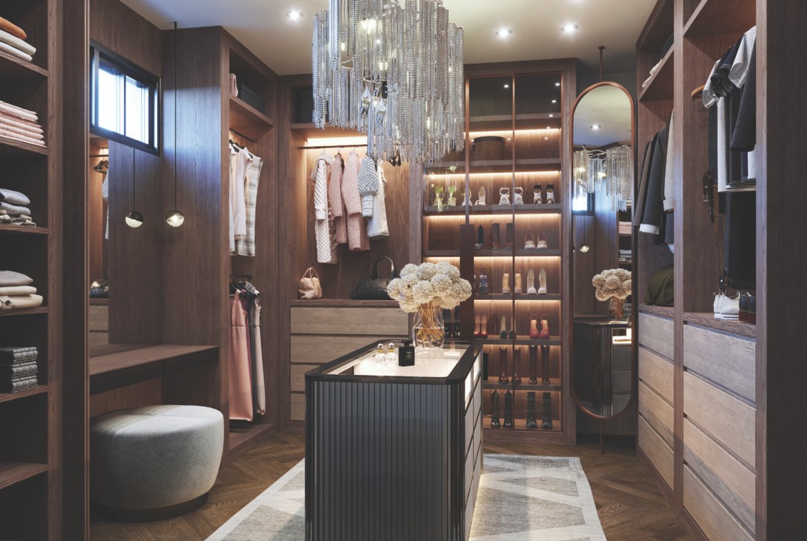 A luxurious walk-in closet with wooden shelves filled with clothes and shoes, perfect for new homes. A central island is adorned with decorative flowers under a glamorous crystal chandelier. Soft lighting creates a warm ambiance, highlighting elegant décor and design.