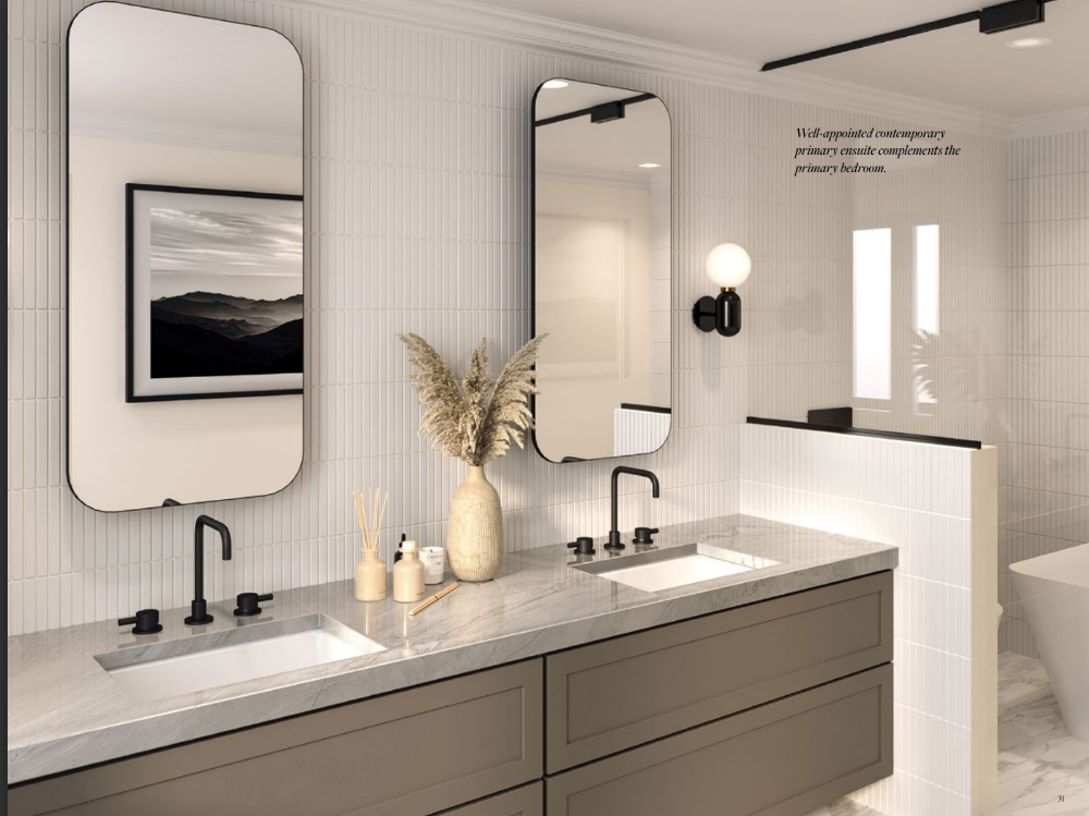 A modern bathroom in new condos in GTA features two rectangular mirrors above a double sink vanity with sleek black faucets. Neutral decor includes a vase with pampas grass and a reed diffuser. A wall-mounted light fixture and framed landscape art complete the setting, reflecting contemporary style.