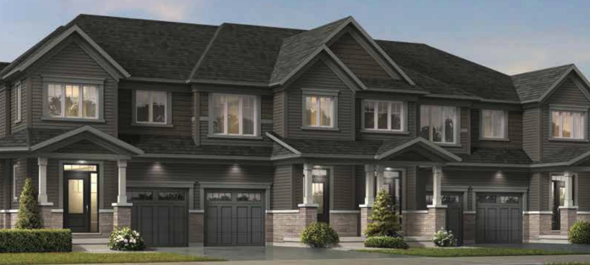 A modern townhouse complex in Brampton with four connected units, each boasting a garage, a front porch, and multiple windows. The exterior showcases a gray and stone color scheme with small shrubs and trees in front. The clear sky suggests it's a sunny day—ideal for new home seekers.