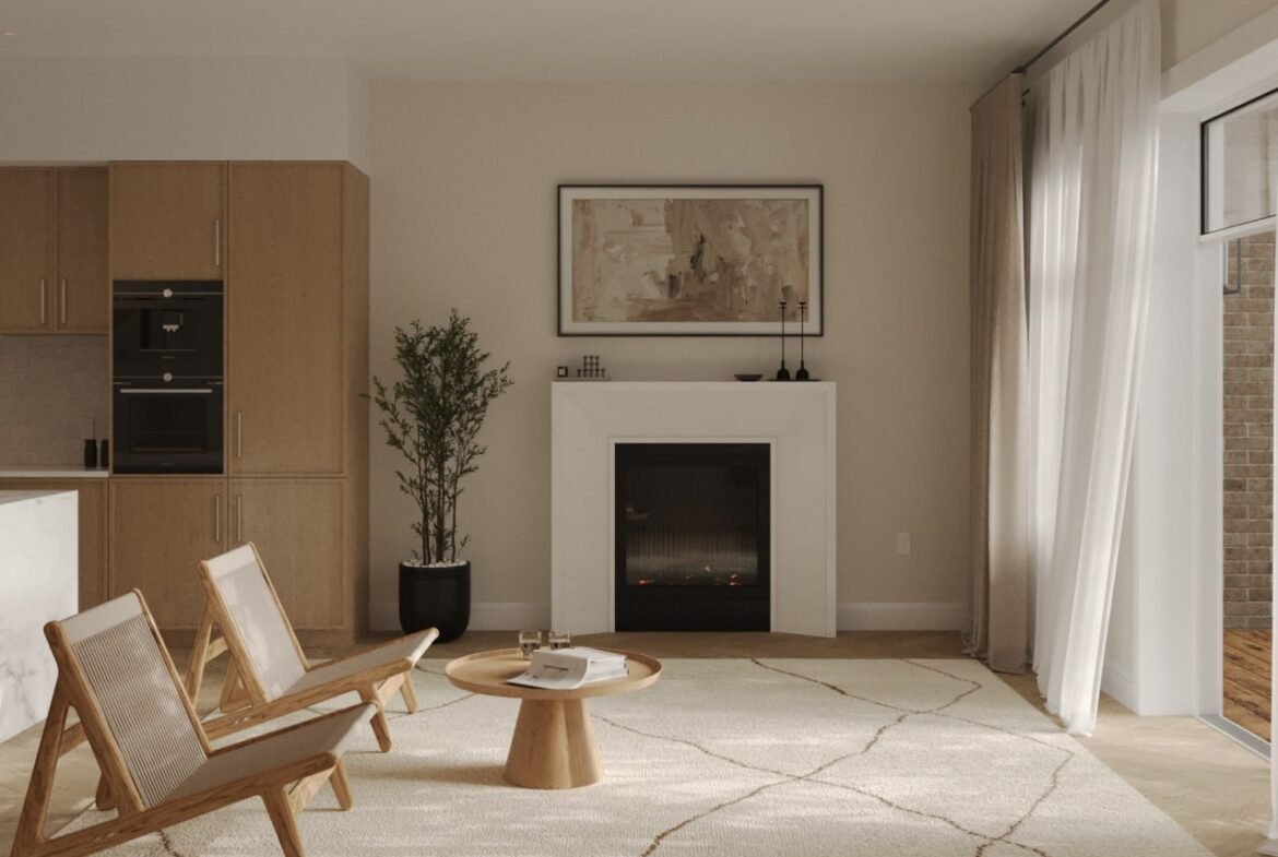 A modern living room with a minimalist design showcases two wooden chairs, a small round table, and a fireplace adorned with framed artwork. Sunlight bathes the space through large windows with sheer curtains, creating an inviting atmosphere that's perfect for new condos in GTA.