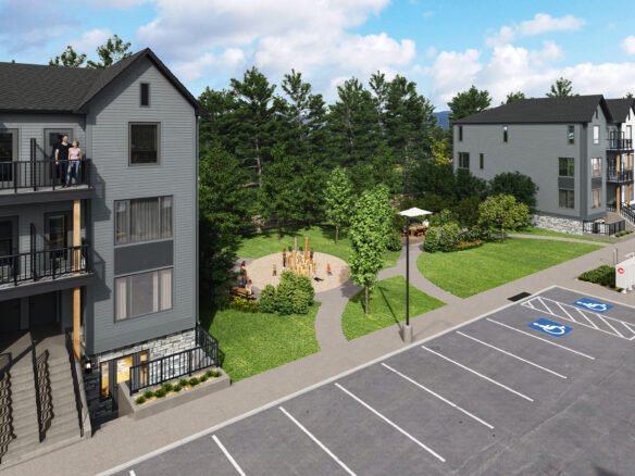 A birds-eye view of a modern apartment complex featuring multiple three-story buildings showcases new homes. A small park with a playground is situated between the buildings. In the foreground, a parking lot includes marked accessible spaces, while trees border this inviting area.