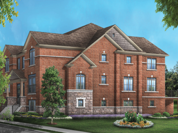 A spacious two-story brick house with multiple gables and windows stands against a blue sky. The front yard showcases well-maintained greenery and a flower bed, while trees frame the scene. Ideal for those exploring new homes, this property exudes charm and comfort.