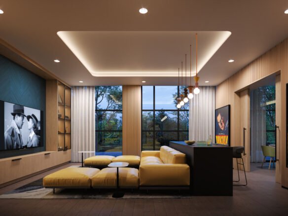 A modern living room in Mile & Creek 3 Condos features a large yellow sectional sofa, surrounded by black-and-white movie posters and a flat-screen TV showcasing a classic film. Large windows overlook lush trees, while pendant lights elegantly illuminate the cozy Mile Creek seating area.
