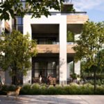 A modern condo building, Mile & Creek, boasts large balconies enveloped by lush trees and greenery. Two people relax on a balcony while another walks their dog on the sunlit sidewalk, creating a blissful scene.
