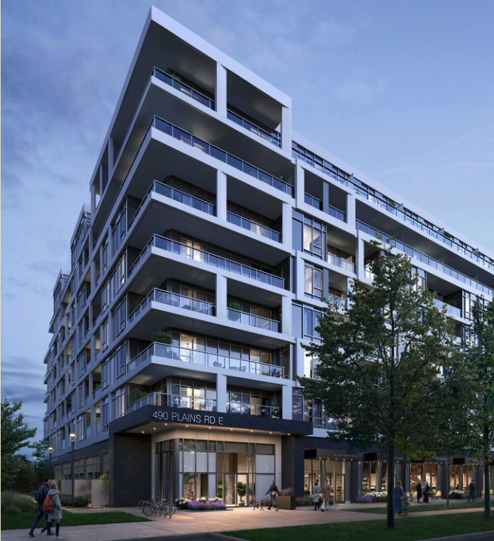 A modern multi-story apartment building at twilight features numerous balconies and large windows, showcasing new homes with contemporary design. The address "490 Plains Rd E" is visible on the facade, surrounded by trees and a bike rack. The sky is partly cloudy, adding to the serene streetscape.