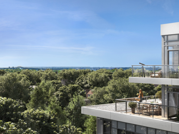 A modern, multi-story building with large glass windows and balconies overlooks a lush green forest. A person stands on a balcony enjoying the view under a clear blue sky, epitomizing the appeal of new homes in Brampton for those craving a scenic escape.