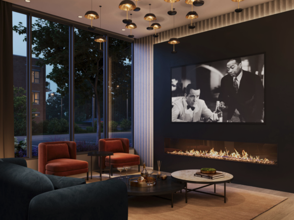 A modern living room in new homes features a sleek fireplace, a large black-and-white movie still on the wall, two orange armchairs, a dark sofa, and a round coffee table. Floor-to-ceiling windows reveal an evening cityscape, while hanging lights add warmth.