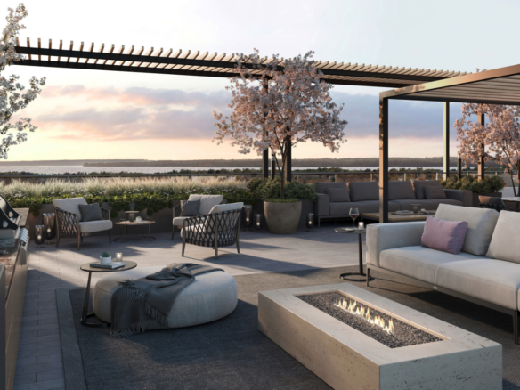 A modern rooftop patio in one of the new homes in Toronto features comfortable seating around a rectangular fire pit. Blossoming trees and potted plants decorate the space. The setting sun casts a warm glow over the relaxed ambiance, with a view of nature in the background.