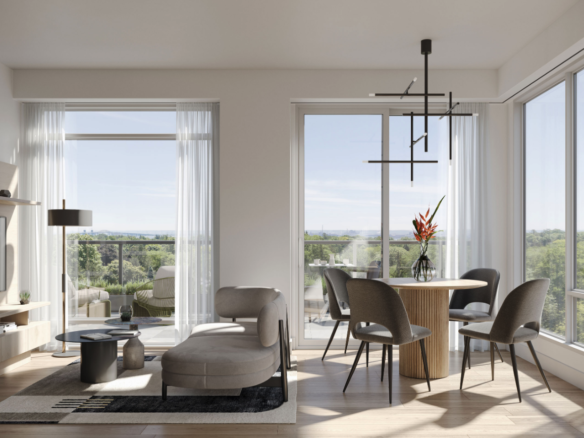 A modern living room with large windows overlooking a scenic view. The room features a cozy sofa, a small coffee table, and a round dining table with chairs. A contemporary chandelier hangs from the ceiling, and a vase with flowers decorates the table—perfect for those exploring new condos in Brampton.